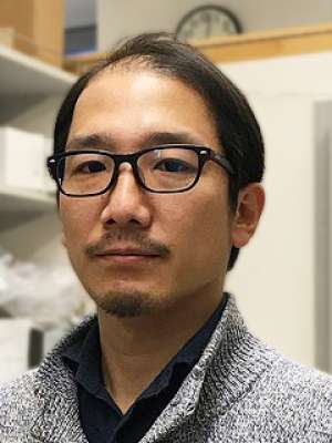 Headshot of a man wearing glasses in a workspace.