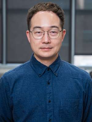Headshot of Doctor Young Do Koo in a blue button-down shirt and wearing glasses