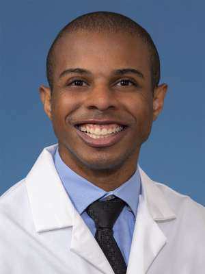 Head shot of Paul Lewis, MD, MS in white coat, smiling at camera