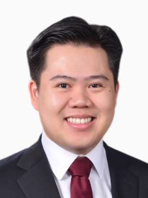 Smiling man in dark suit and maroon tie, professional headshot