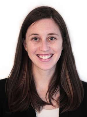 Headshot of smiling woman with long dark hair wearing black blazer on white background