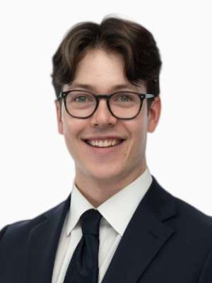 Young man in suit and glasses smiling on white background.
