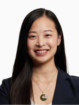 Smiling woman with long dark hair wearing a blazer and circular pendant necklace