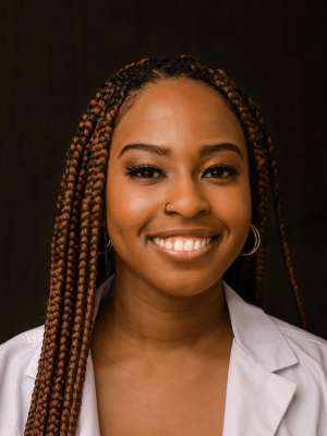 Head shot of Angela Udongwo in a white coat, smiling at the camera