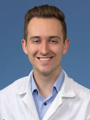 Head shot of Brendan Colgan MD, in white coat, smiling at camera