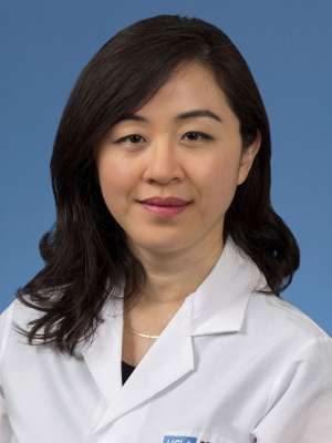 Head shot of Irma Zhang in a white coat, smiling at camera.
