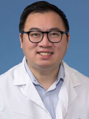 Head shot of John Nguyen in white lab coat, smiling at camera