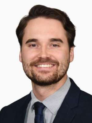 Smiling man in navy suit and tie on white background