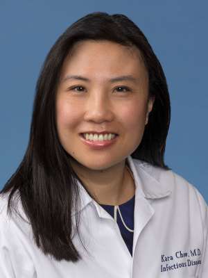 Kara Chew smiling in a white coat against a blue background.