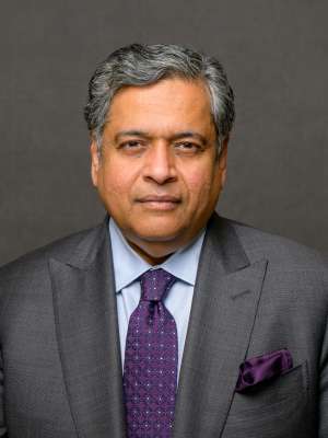 Person in gray suit with purple tie and pocket square on gray background