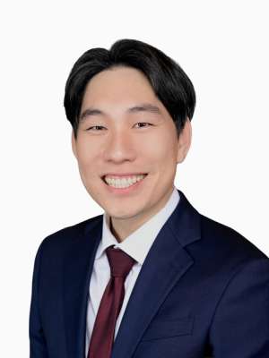Smiling man in navy suit and maroon tie on white background