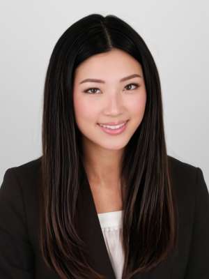 Smiling woman in black blazer with long dark hair against light background