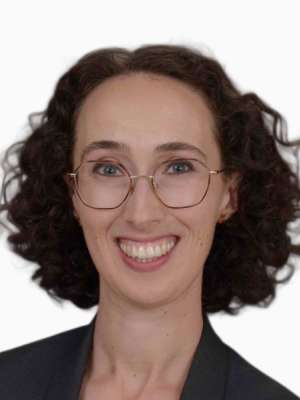 Hannah Chute smiling headshot with curly hair, glasses, and dark blazer