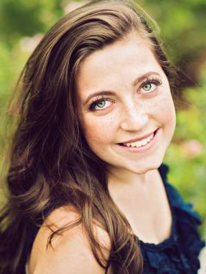 Mackenzie Berube, Editorial Coordinator, posing outdoors in soft sunlight.