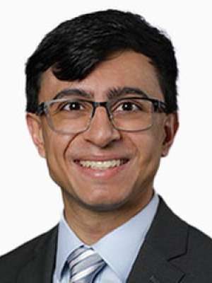 Jaha Nikhil smiling headshot wearing glasses and a suit and tie