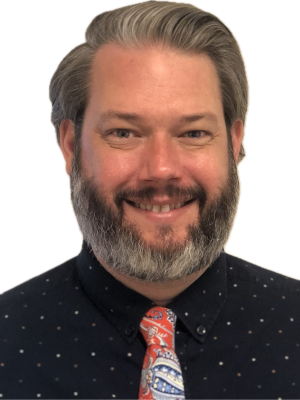 Bear Waters with salt-and-pepper beard wearing dark dotted shirt and colorful tie