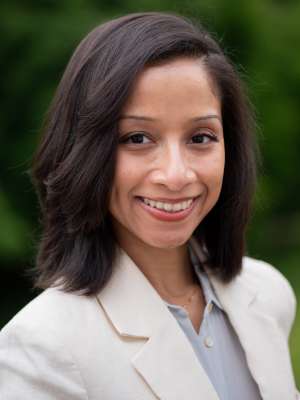 Head-and-shoulders portrait of a person in a white blazer outdoors