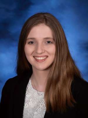 Professional headshot of a smiling woman against a blue backdrop.