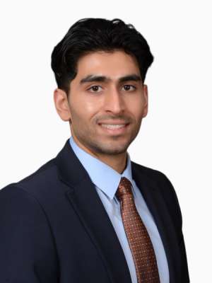 Neal Mahajan, professional headshot wearing navy suit and brown tie, smiling