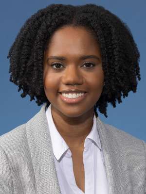 Smiling headshot of woman with natural hair wearing a light blazer