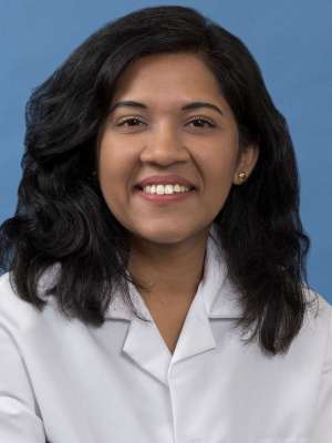 White coat head shot of Darshana Vijaywargiya, smiling at the camera