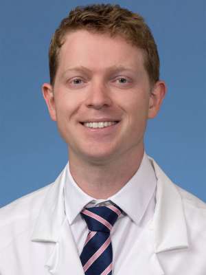 Head shot of Sebastian Green in white lab coat, smiling at camera