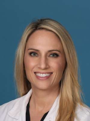 Portrait of Anna L. Houterman, MD, wearing a white lab coat against a blue background.
