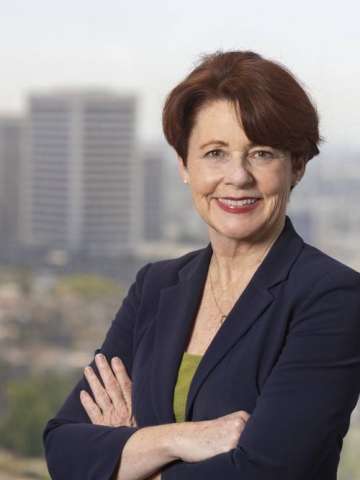 Karen A. Grimley in a dark suit stands with arms crossed, smiling, exuding professionalism.