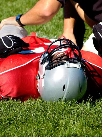 Injured American football player laying on a grass