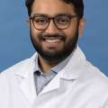 White coat head shot of Jason Gandhi, smiling at the camera