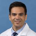 White coat head shot of Christopher Hernandez, smiling at the camera
