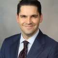 Man smiling while wearing navy blue suit and tie