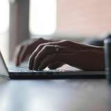 A person writes on a laptop.