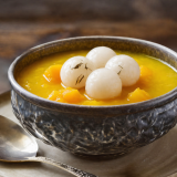 Pumpkin Porridge bowl topped with three white rice dumplings