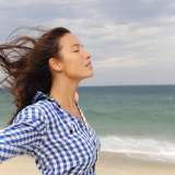 A woman feels the breeze at the beach.