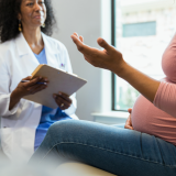 A pregnant woman speaks with her doctor.
