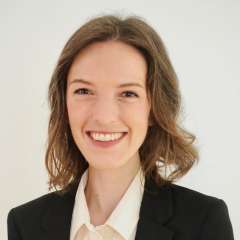 A woman with brown hair, wearing a suit jacket with a white shirt