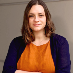 Headshot of Tara TeSlas in orange shirt and black cardigan