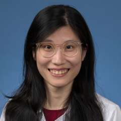 Head shot of Megan Cheng in white lab coat, smiling at camera