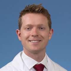 Dr. Sebastian Green in a white coat and tie smiling 