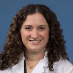 Head shot of Alexa Ciarolla in white lab coat, smiling at camera