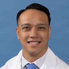 White coat head shot of Michael Arias, smiling at the camera