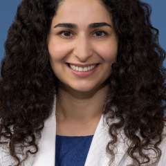 Head shot of Nicki Karimi-Mostowfi, MD in white coat, smiling at the camera