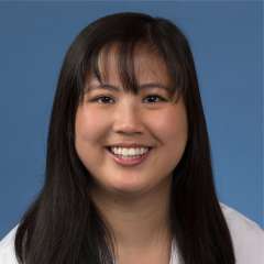 Head shot of Maia Giombetti in white lab coat, smiling at camera