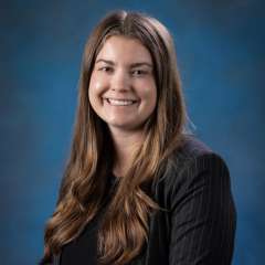 Head shot of Chloe Villars, MD in a dark top, smiling at camera