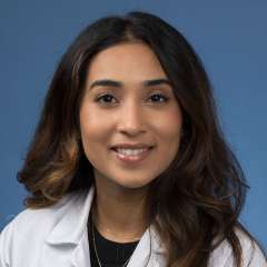 Head shot of Ashni Patel in white lab coat, smiling at camera