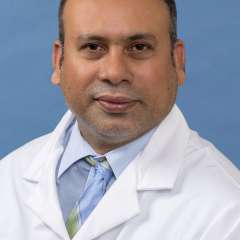 White coat head shot of Sabir Syed, giving a small smile at the camera
