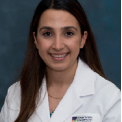 A woman with long black hair, wearing a resident physician's coat