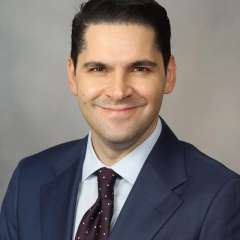 Man smiling while wearing navy blue suit and tie