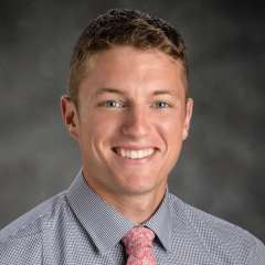 Bryan Myers Headshot in an indoor setting with a gray baackground